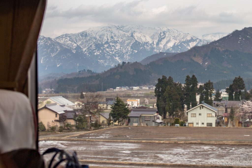 snötäckta bergstoppar, japansk landsbygd på östkusten, när de japanska alperna. Tågresa.
